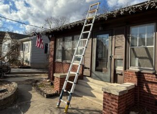 Werner TS1250 telescoping ladder, fully extended at 12.5 feet reaches from the driveway to past the roof or a brown ranch home that still has Christmas icicle lights on it.